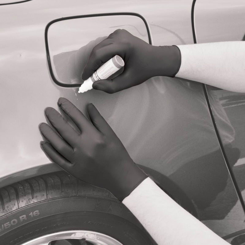 Person applying a product to a car mirror with gloves on